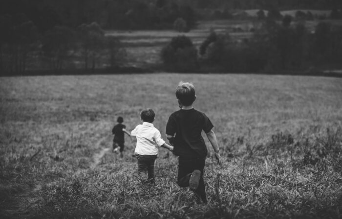 three boys running on field