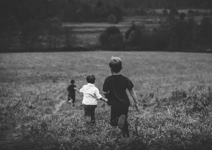 three boys running on field