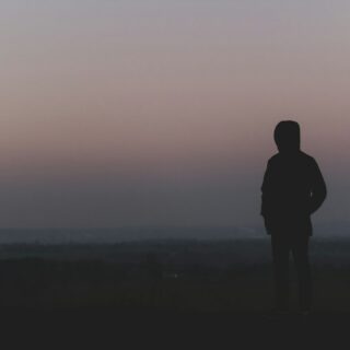 silhouette of man standing on hill during sunset