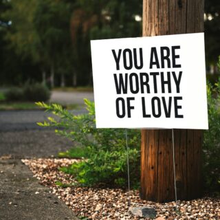 you are worthy of love sign beside tree and road