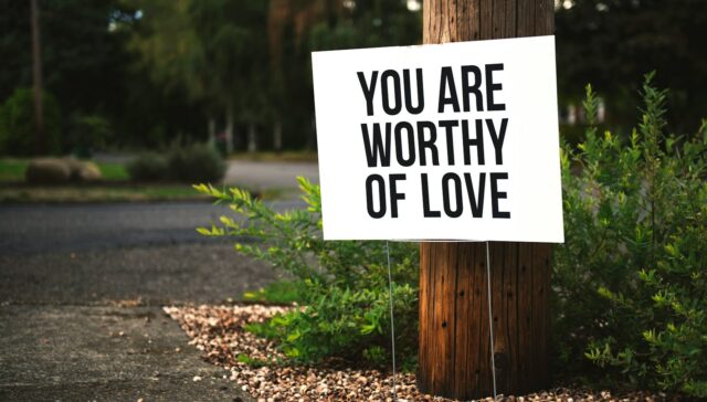 you are worthy of love sign beside tree and road