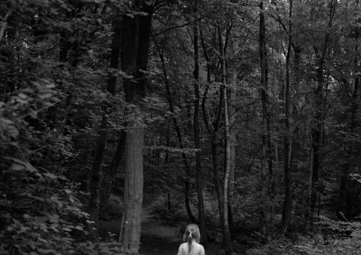 A girl in a white dress walks through a serene forest, capturing a moment of exploration and wonder.