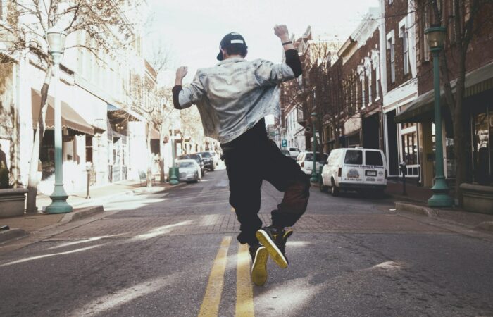 man jumping on the middle of the street during daytime