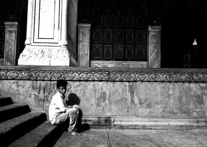 A young boy sitting on historic steps in Delhi, conveying solitude and contemplation.