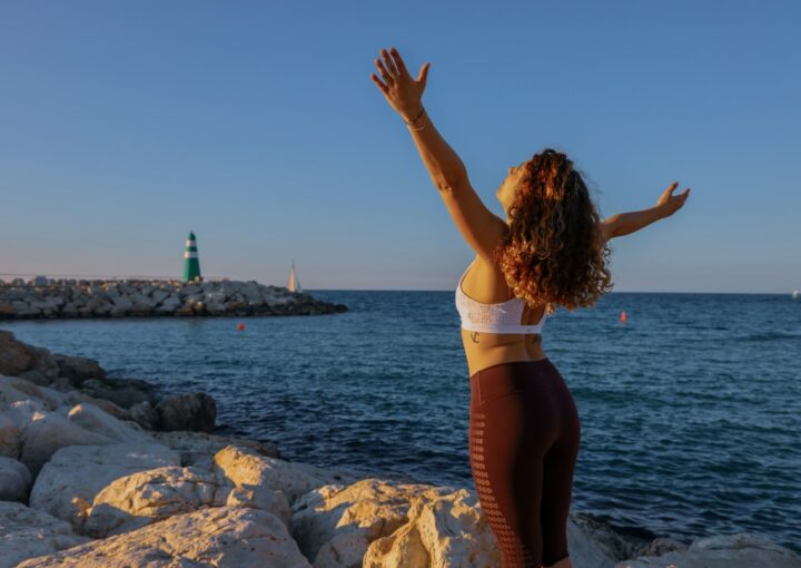 woman in white sports bra and black bottoms standing on seashore