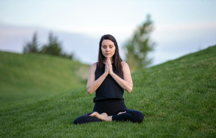 woman in black tank top and black pants sitting on green grass field during daytime