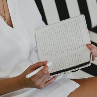 woman in white button up shirt holding white braille paper