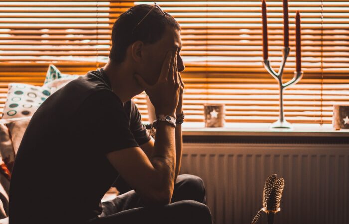 man sitting on chair covering his eyes