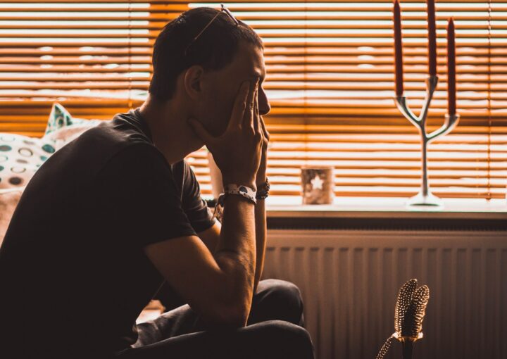 man sitting on chair covering his eyes