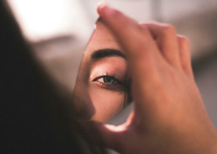 A captivating image of a woman's eye reflected in a broken mirror piece with soft lighting.