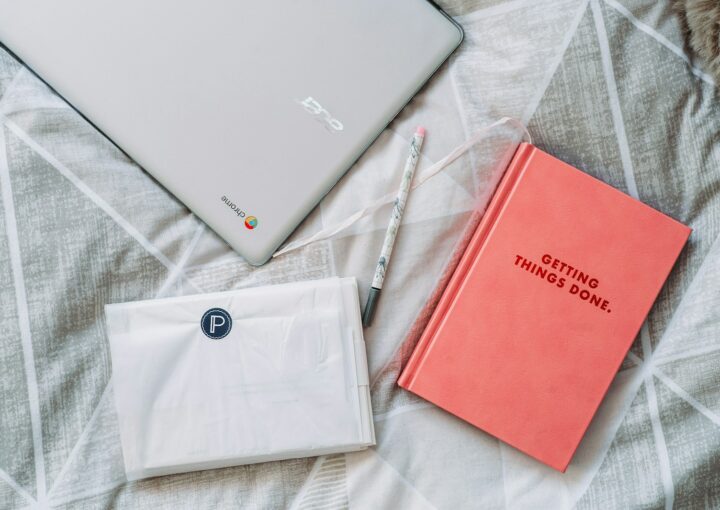 Getting Things Done book beside gray Acer Chromebook on gray textile