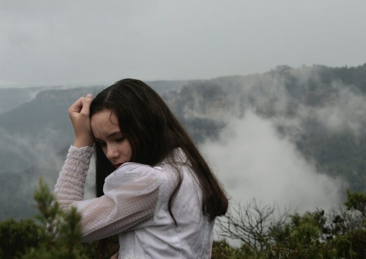 woman in white sweater covering her face with her hands