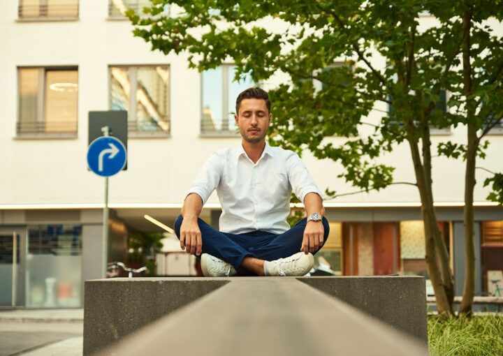 man in white dress shirt sitting on gray concrete bench during daytime