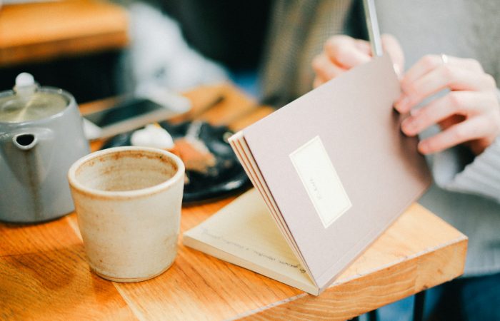 person opening book near coffee cip