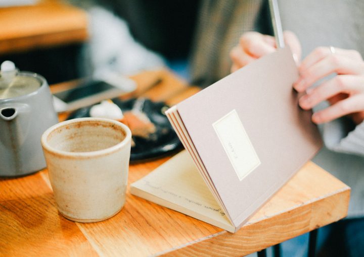 person opening book near coffee cip