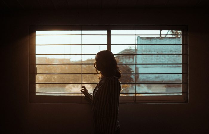 woman in white and black stripe shirt standing near window