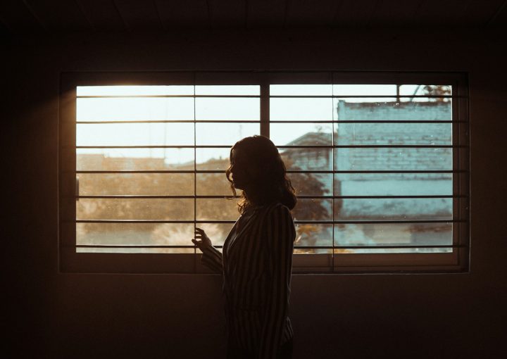woman in white and black stripe shirt standing near window
