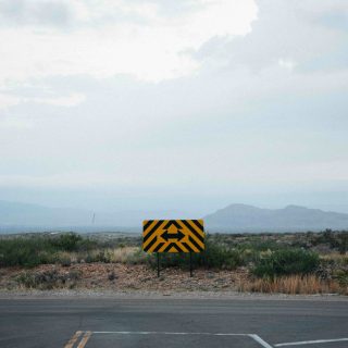 a yellow and black sign sitting on the side of a road