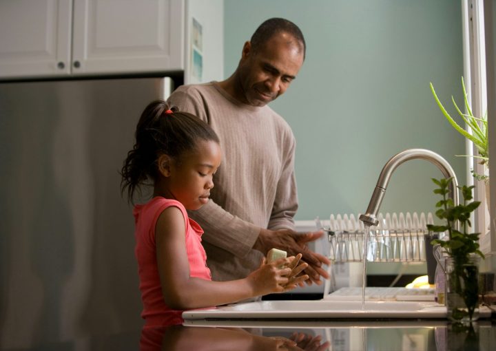 man in long sleeve shirt standing beside girl in pink tank top washing hands