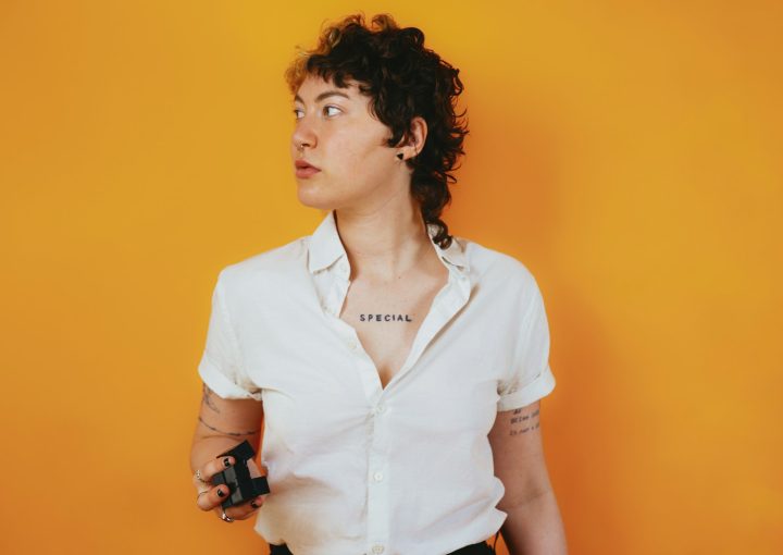Portrait of a nonbinary autistic person in a studio setting with a stim toy in their hand