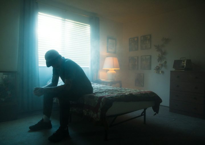 man in black jacket sitting on bed