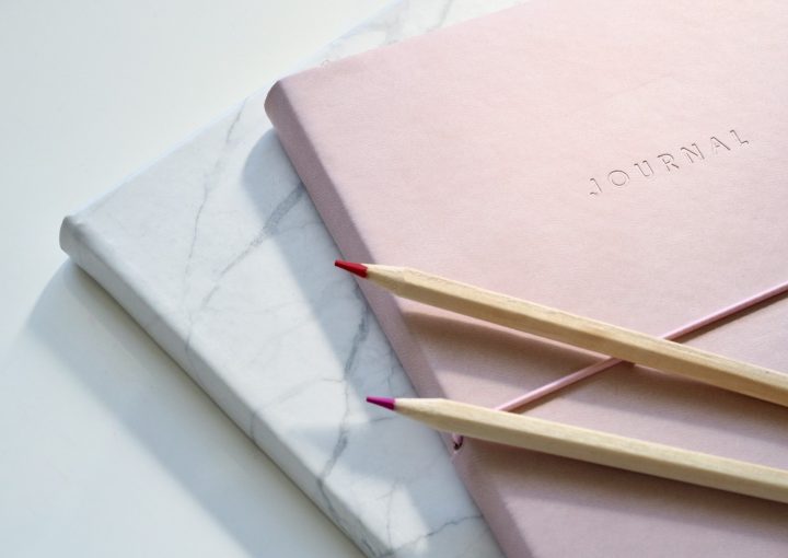 red and purple coloring pencils on pink journal