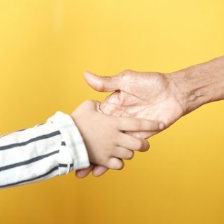 a person holding a child's hand with a yellow background