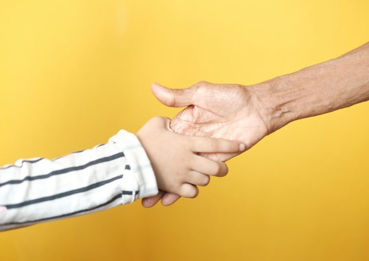 a person holding a child's hand with a yellow background