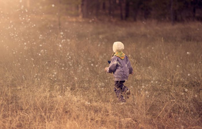 A young child runs through a grassy field during sunset, enjoying the freedom of outdoor play.