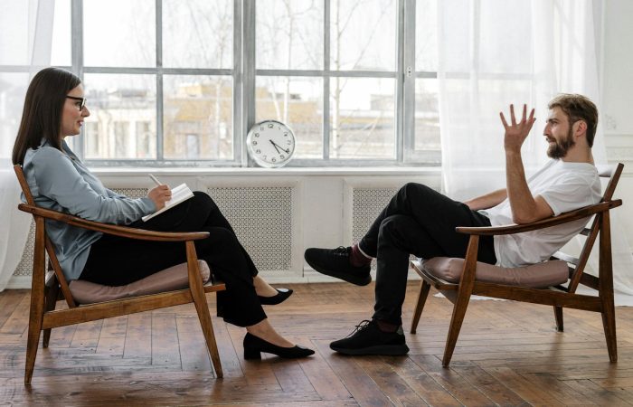 A therapist engaging in a counseling session with a male patient to support mental health.