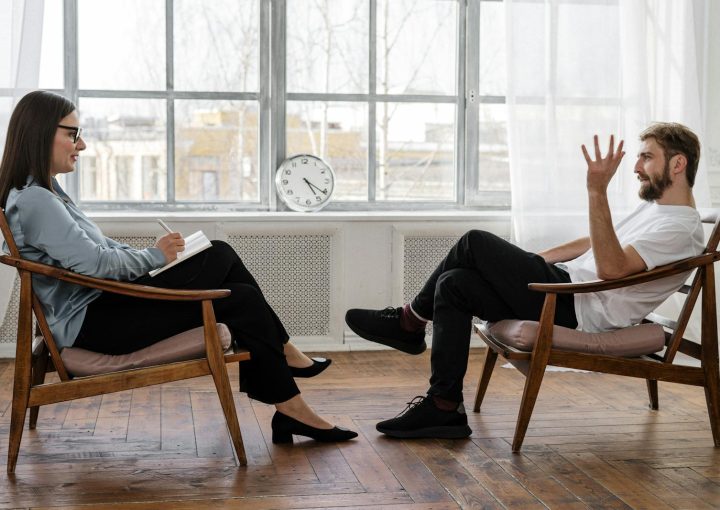 A therapist engaging in a counseling session with a male patient to support mental health.
