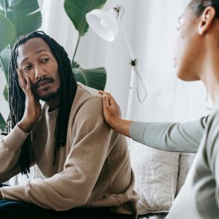 Two diverse individuals having an empathetic conversation in a cozy indoor setting.