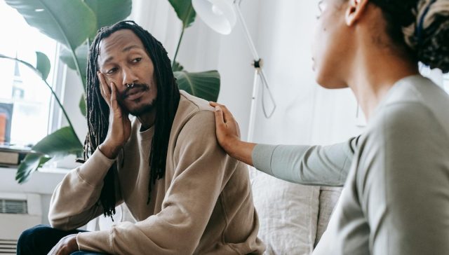 Two diverse individuals having an empathetic conversation in a cozy indoor setting.