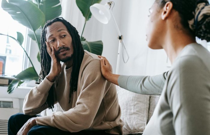 Two diverse individuals having an empathetic conversation in a cozy indoor setting.