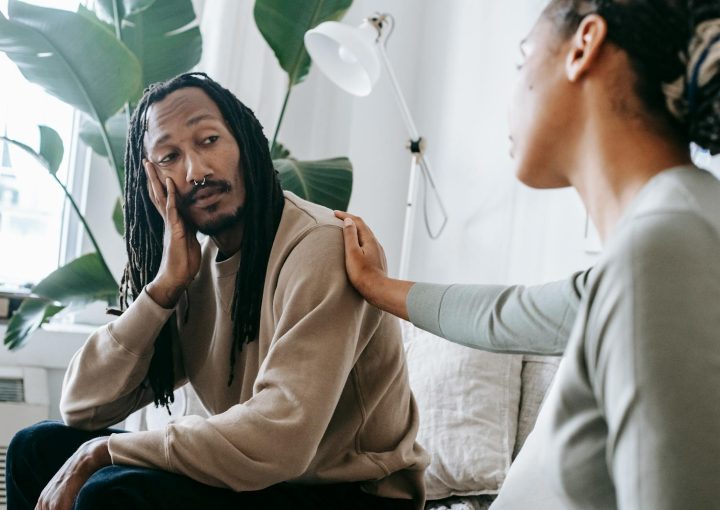 Two diverse individuals having an empathetic conversation in a cozy indoor setting.