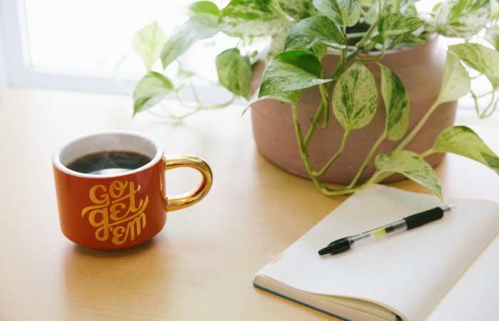 black retractable pen on opened book beside red and white go get'em-printed coffee cup