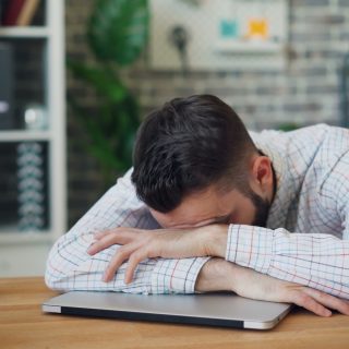 a man sitting at a desk with his head in his hands