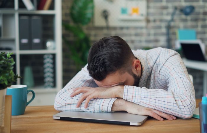 a man sitting at a desk with his head in his hands