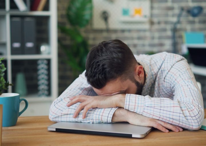 a man sitting at a desk with his head in his hands