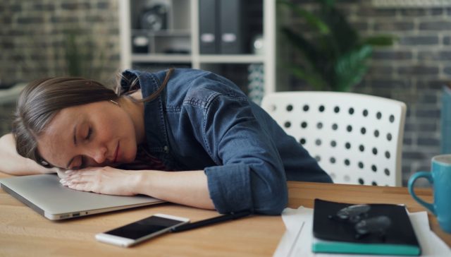 a woman laying her head on a laptop