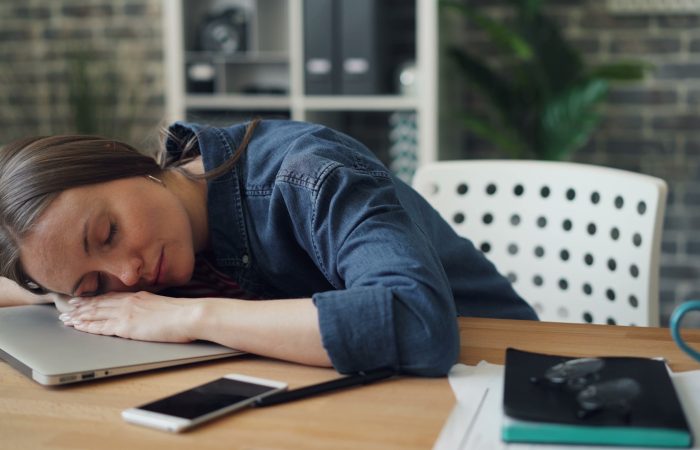 a woman laying her head on a laptop