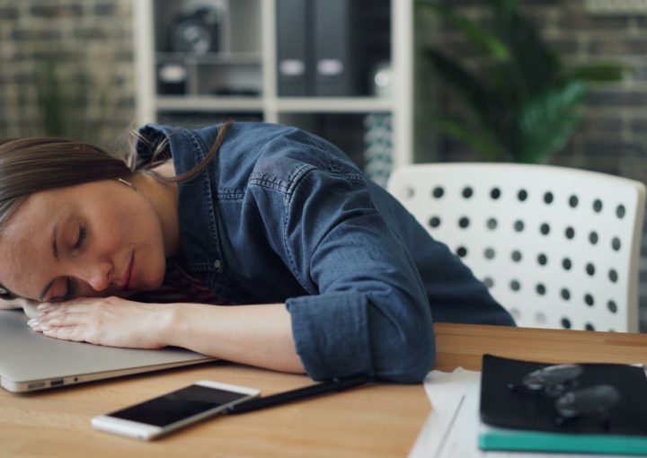 a woman laying her head on a laptop