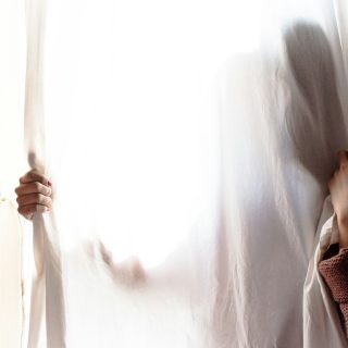 person hiding on white curtain