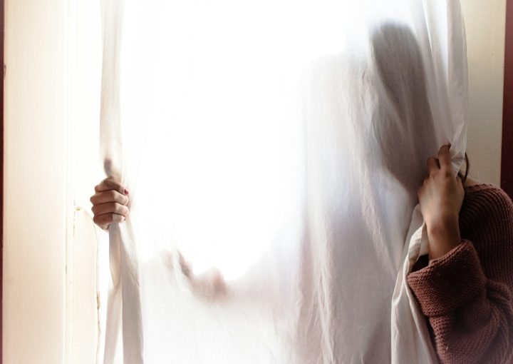 person hiding on white curtain