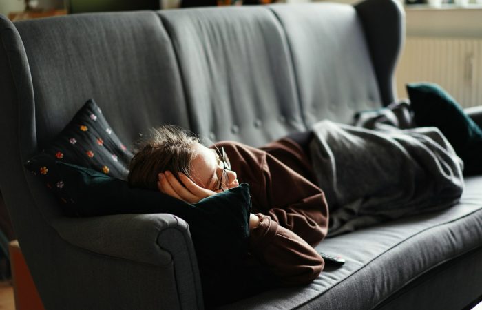 woman in pink jacket lying on gray couch