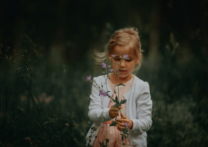 selective-focus photography of girl holding flower