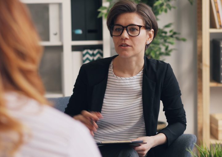 a woman sitting on a couch talking to another woman