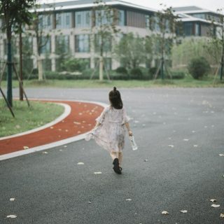 girl holding clear plastic bottle walking on road