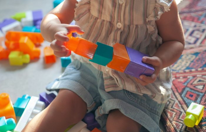 girl in brown button up shirt holding blue and orange plastic toy