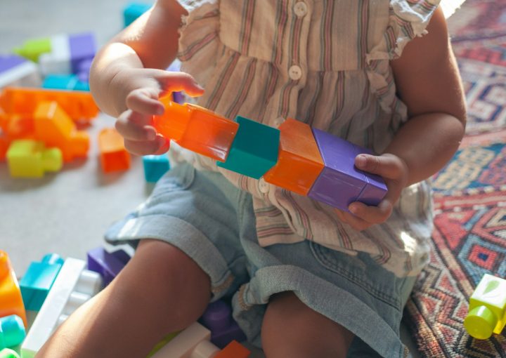 girl in brown button up shirt holding blue and orange plastic toy